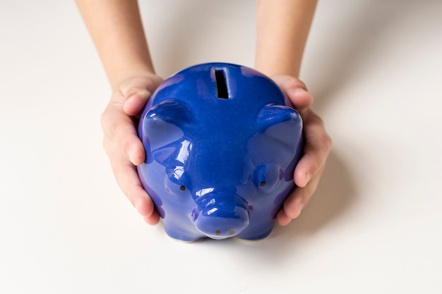 Blue piggy bank being held in hands