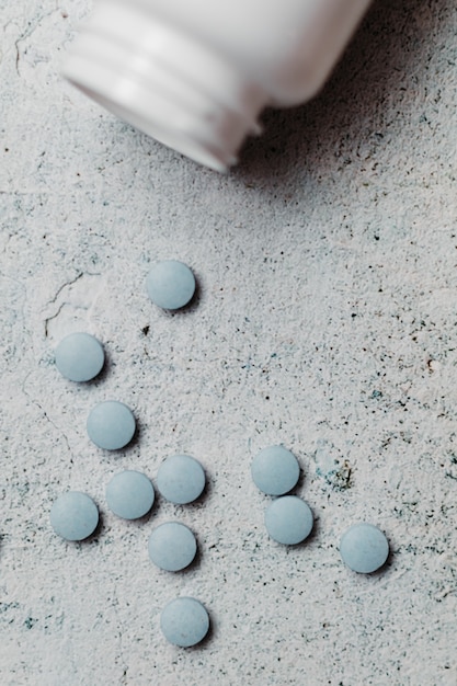 Blue pills and canister on concrete background