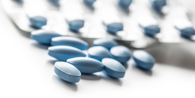 Blue pills loose lying on a white isolated background.