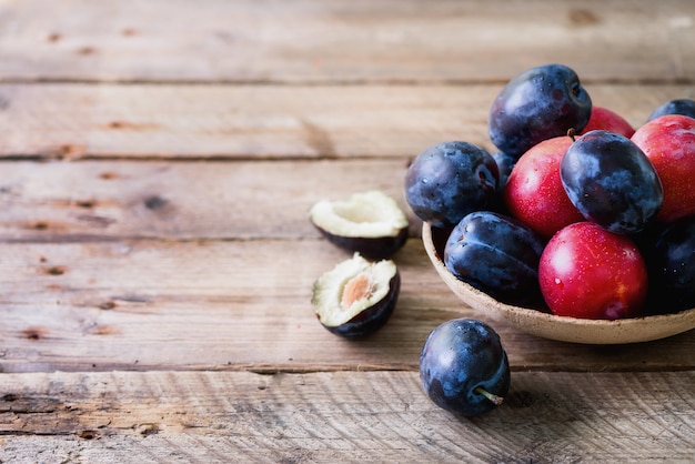 Blue and pink organic plums on dark wooden. 