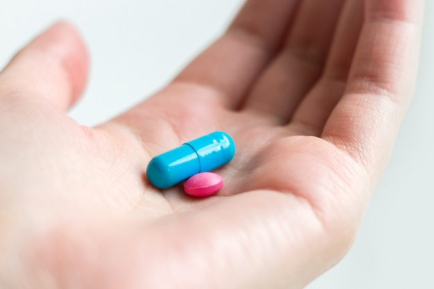 Blue and pink pill capsule on the female palm on white background. Antidepressant pills in female hand.