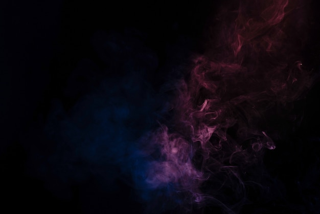 Blue and pink steam on a black surface. Copy space.