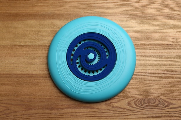 Blue plastic frisbee disk on wooden background top view