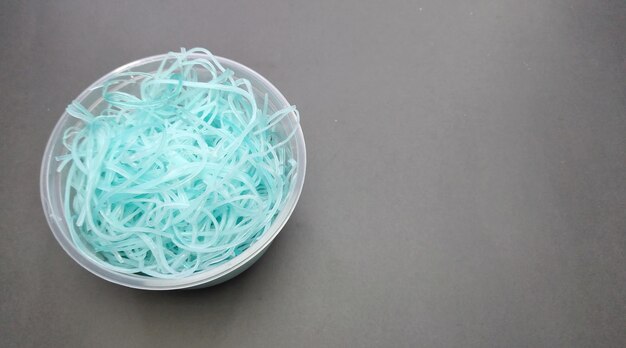 青いプラスチック製のヌードルを灰色の背景の上から見る