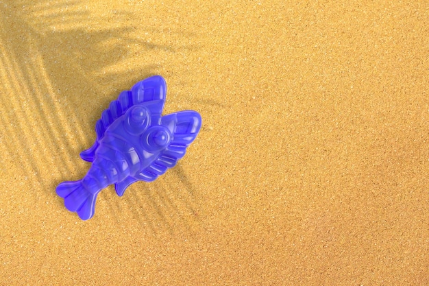 Blue plastic shrimp on sand beach background closeup Childrens toys for bathing babies Educational games for children preschool education Layout preparation of toys for the designer or website