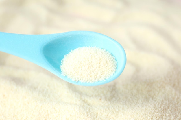 Blue plastic spoon with powdered milk, close up