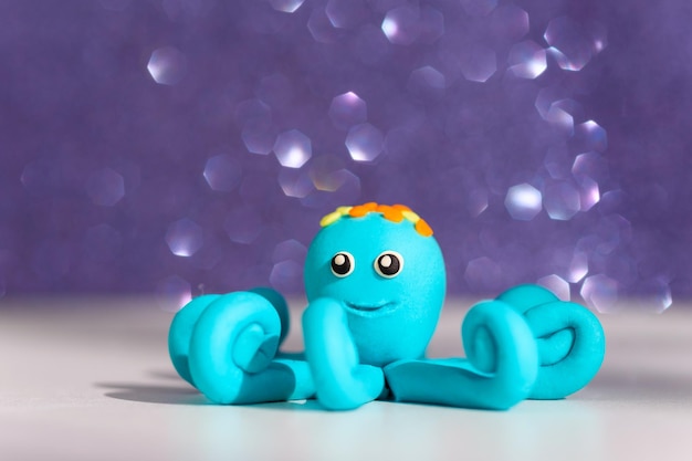 Blue plasticine octopus on purple shimmering shiny background children's games with modeling clay plasticine figures