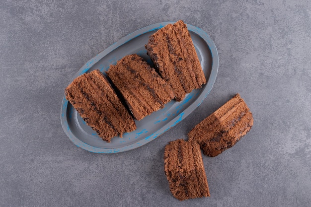 Blue plate of chocolate cake placed on stone table.