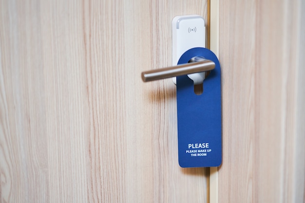 Photo blue plate hanging on the door handle of a hotel room