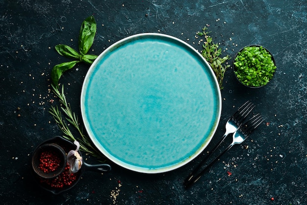 검은 돌 배경에 야채와 향신료가 있는 파란색 접시 상위 뷰 소박한 스타일