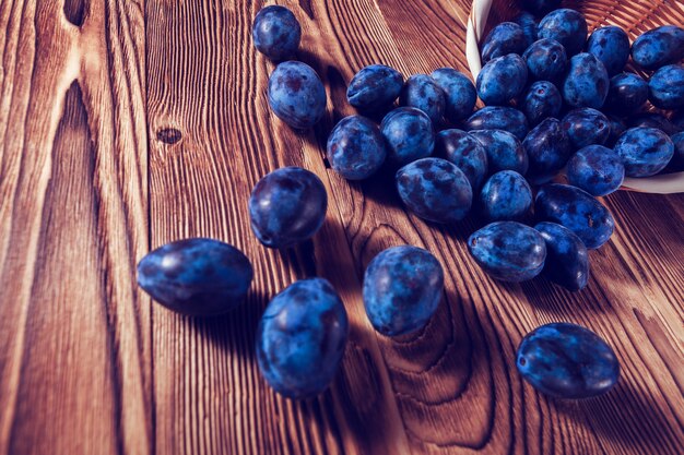 Blue plum spilled on a wooden background