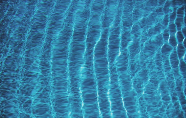 Blue pool water background blurred transparent clear calm water surface texture water waves in sunli