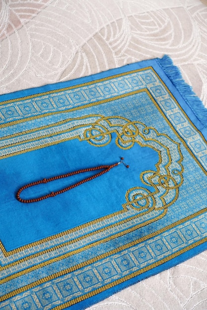 A blue prayer rug in the house of a Muslim his rosary next to it a prayer rug for worship in Islam