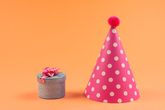 Blue present box with pink bow in a shopping cart and birthday cap