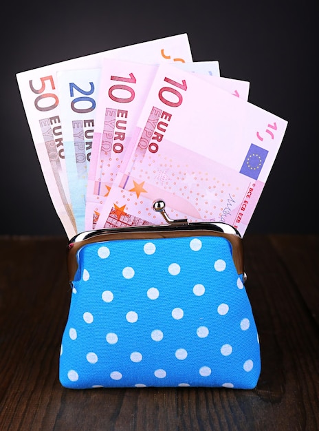 Blue purse with money on table on black background