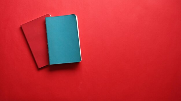 Blue and red notebook on red background Copy space