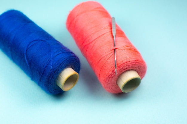 Blue and Red spools of thread with a needle, close up