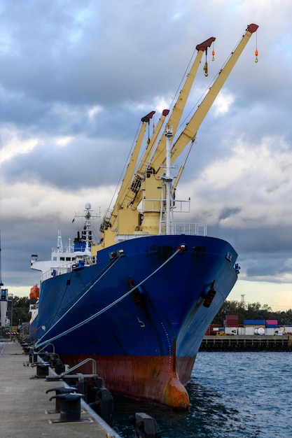 Blue refrigerated cargo vessel moored in port loading of\
cargo