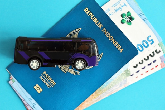 Foto passaporto blu della repubblica dell'indonesia con soldi e autobus giocattolo su sfondo blu da vicino