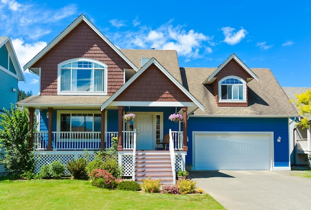 Blue residential house with concrete driveway in front and blue sky background