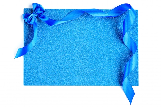 Blue ribbon bow on blue glitter background. Festive background.