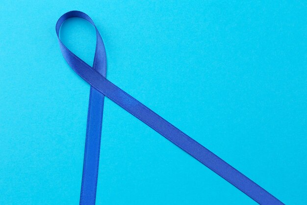 Photo blue ribbon on color background colon cancer concept
