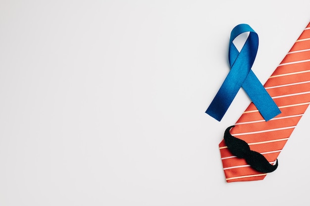 A blue ribbon embellished with a mustache and necktie represents Prostate Cancer Awareness and offers support to patients and their families A symbol of men's healthcare and cancer awareness