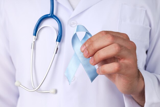 Blue ribbon in male doctor's hand, movember concept