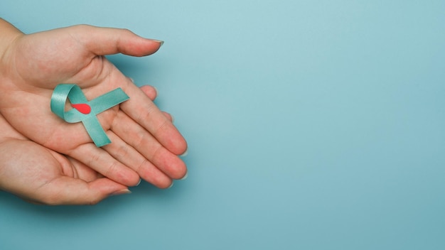 Blue ribbon with a drop of blood in a circle symbol of diabetes day in woman hands World diabetes day Copy space