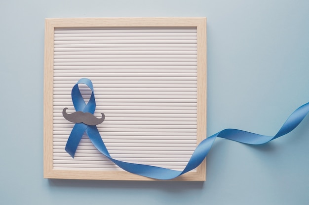 Photo blue ribbon with mustache on letter board, prostate cancer awareness, men health awareness