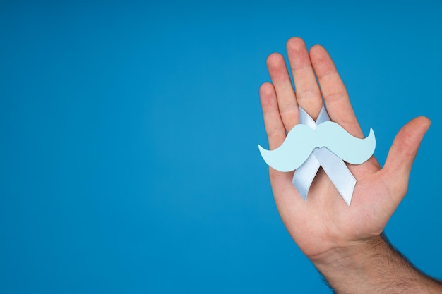 Blue ribbon with a mustache in a man's hand