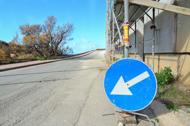 Blue road sign by a metal scaffolding on the edge of the road