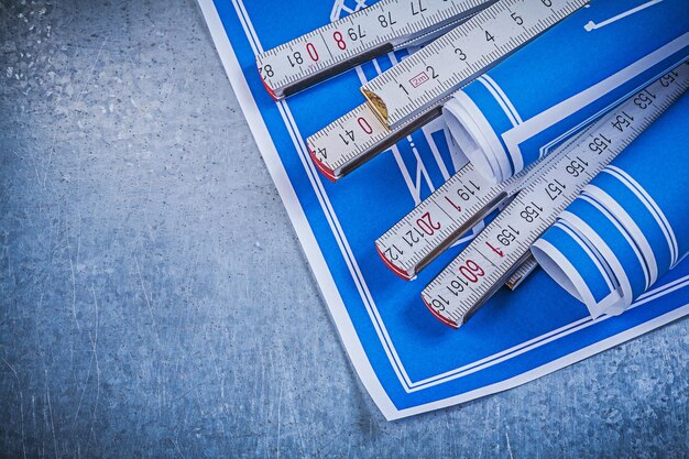 Blue rolled blueprints wooden meter on scratched metallic background