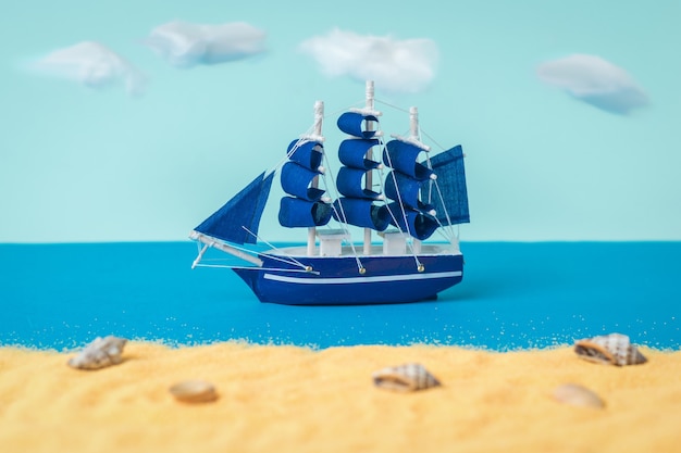 A blue sailboat sailing past a sandy beach. The concept of travel and adventure.