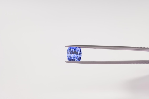 A blue sapphire on a pair of tongs