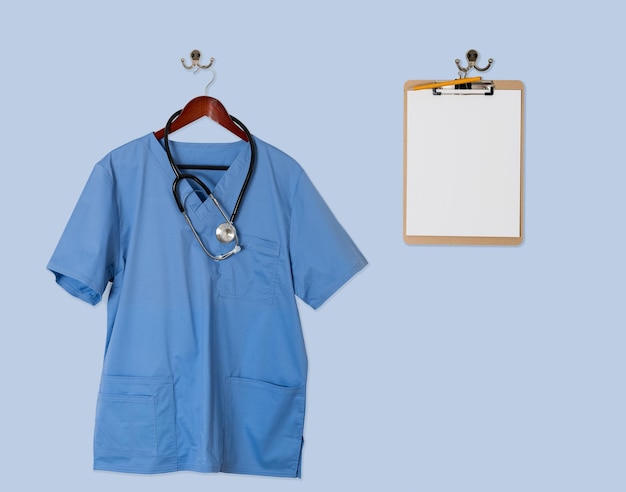 Blue scrubs shirt for medical professional hanging with clipboar