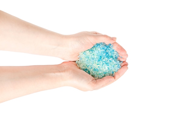 Blue sea salt for a bath in the hands of a girl isolated on white surface.