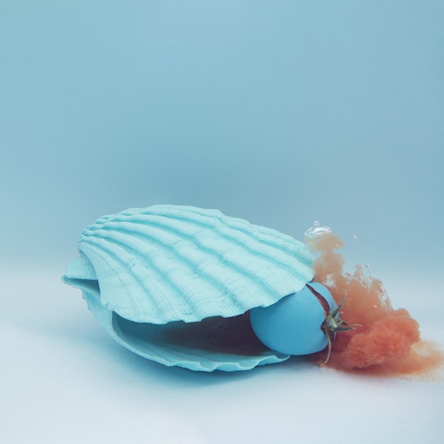 Photo blue sea shell and tomato with juice in the water summer minimal concept with healthy food