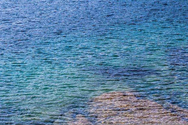 太陽の光の青い海は、表面の背景の夏休みのコンセプトとして輝きます