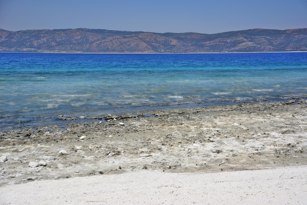 Синее море с белым песчаным пляжем изолировано и горы на заднем плане