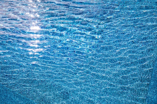 Blue shadows of pool with steps into, sunny summer mood. Ripples water surface, fun recreational