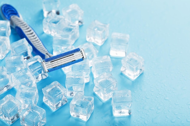 Blue shaving machine with sharp blades on the background of ice
cubes closeup