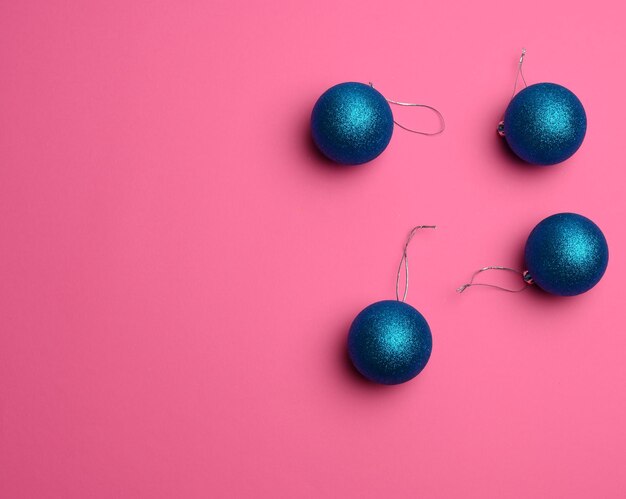 Blue shiny christmas balls on a pink background festive backdrop for christmas and new year copy