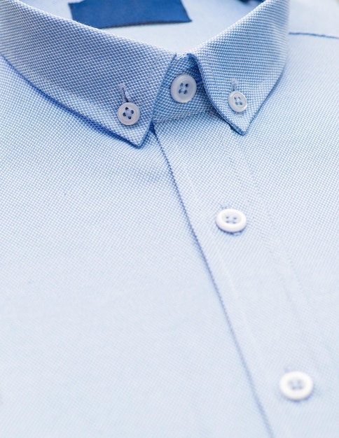 Camicia azzurra con particolare sul colletto e bottone, primo piano