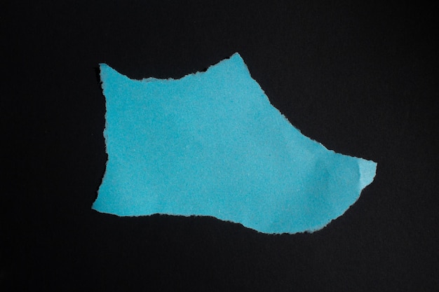 A blue shoe is torn out of a black background.