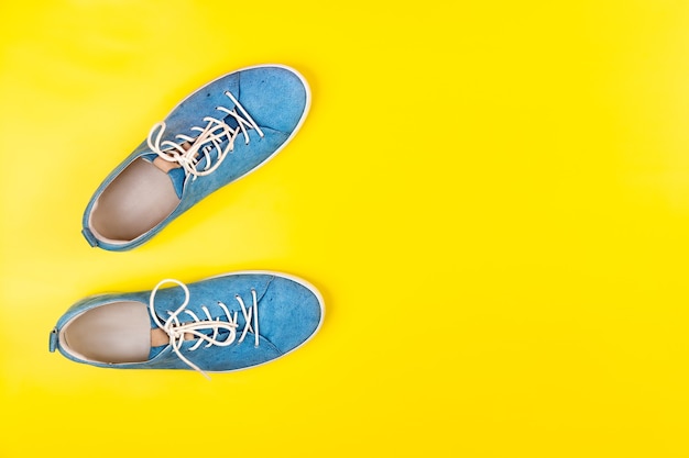 Blue shoes stand on an isolated yellow background