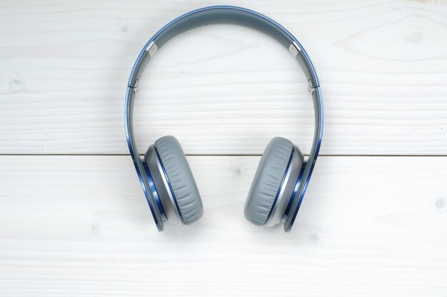 Blue and silver modern headphones for listening to music on a white wood