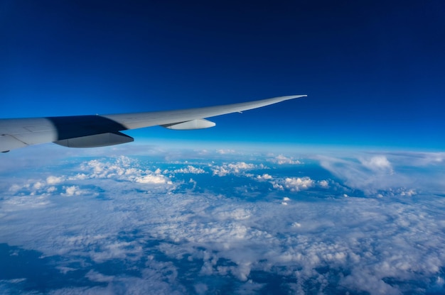 飛んでいる飛行機の翼の下の青い空と雲舷窓からの眺め