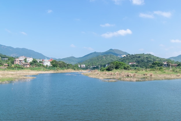 사진 푸른 하늘 녹색 산과 나무가 호수를 둘러싸고 있습니다.