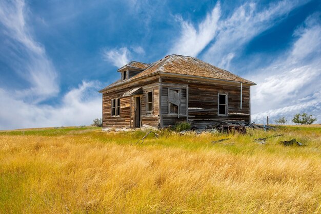 サスカチュワンの大草原のがらくたに囲まれた古い廃屋の上の青い空